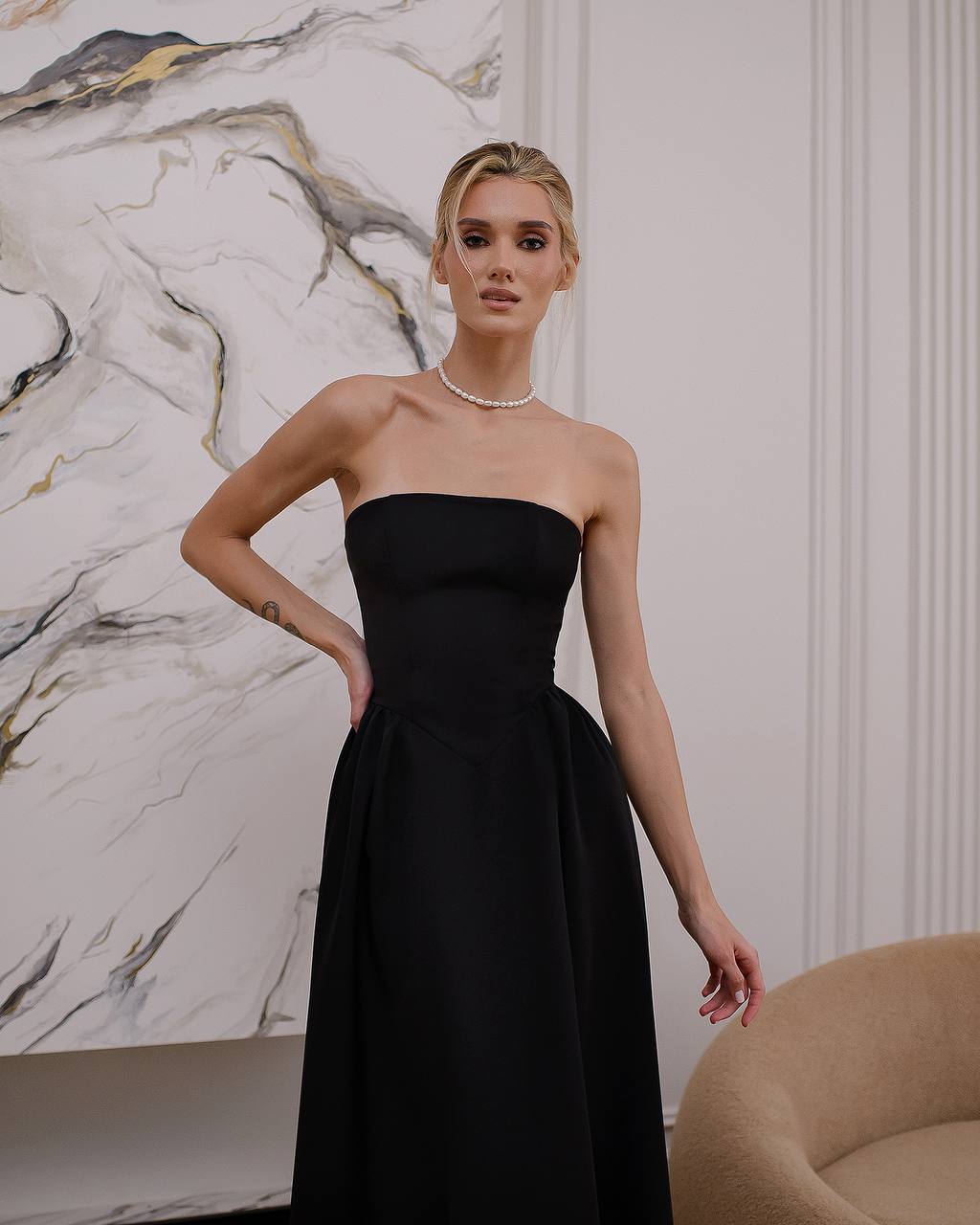 Woman wearing a black strapless gown in an elegant interior setting