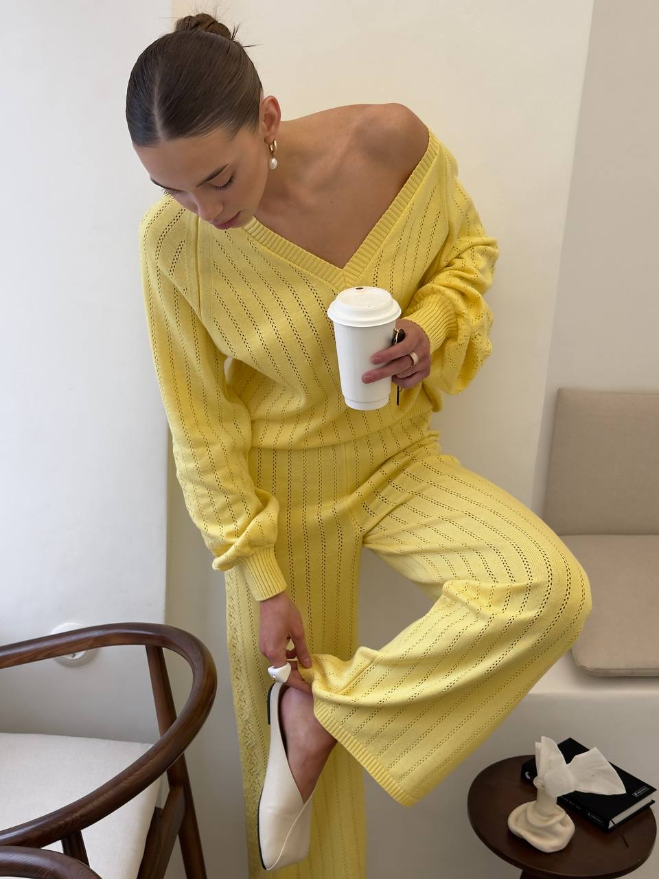 Woman in a yellow outfit holding a coffee cup in a room.