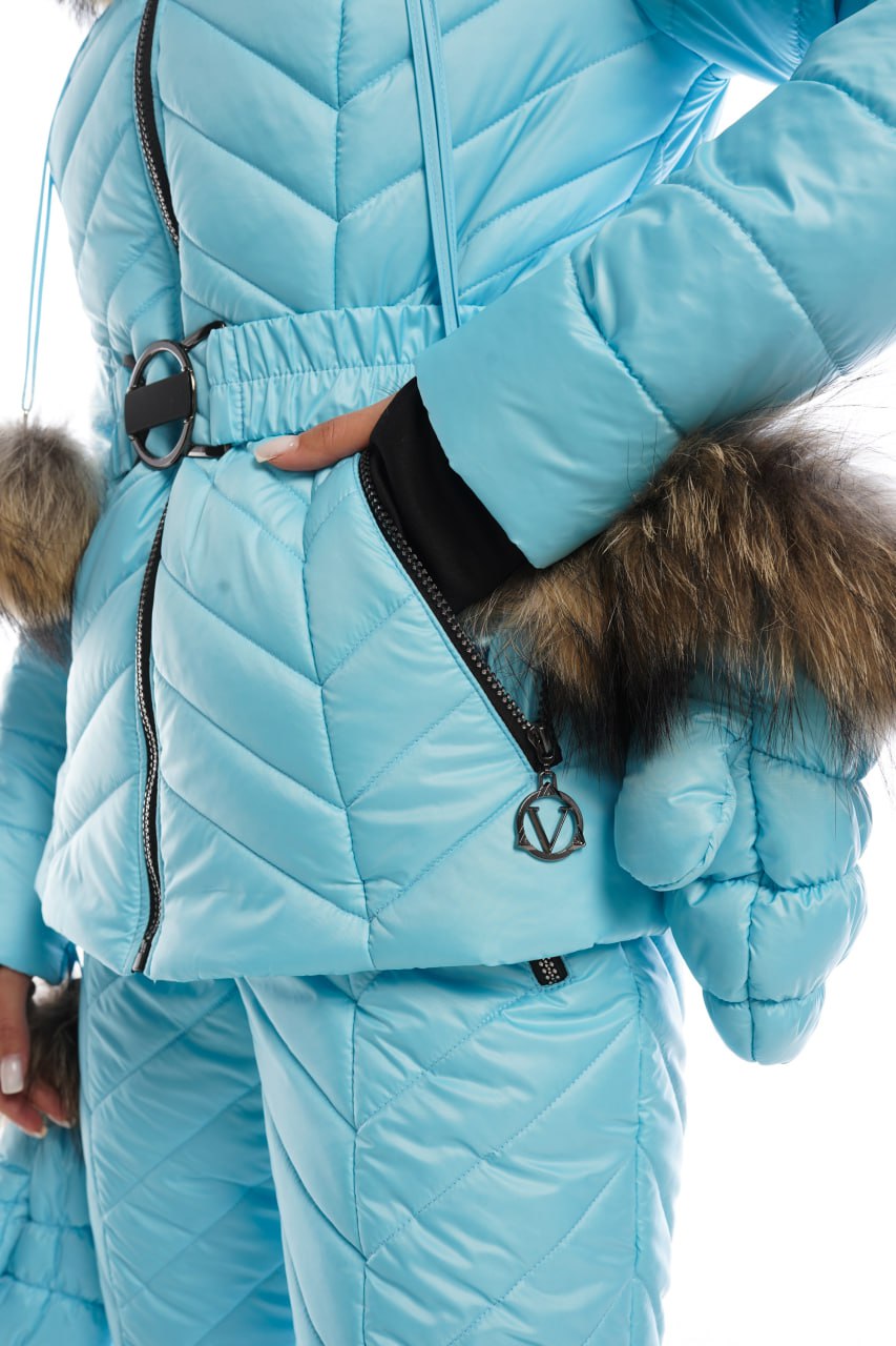 Person wearing a blue winter outfit with fur-lined gloves and hood.