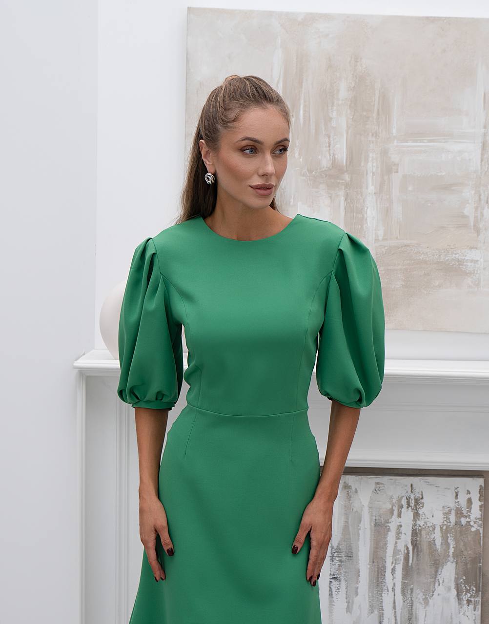Woman wearing a green dress with puffed sleeves against a neutral background