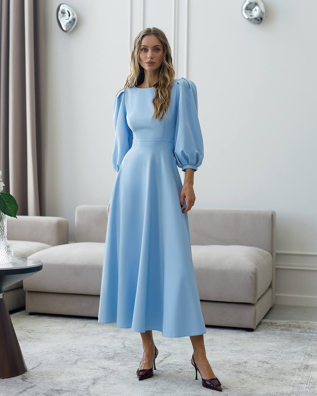 Woman wearing a light blue dress in a modern living room.