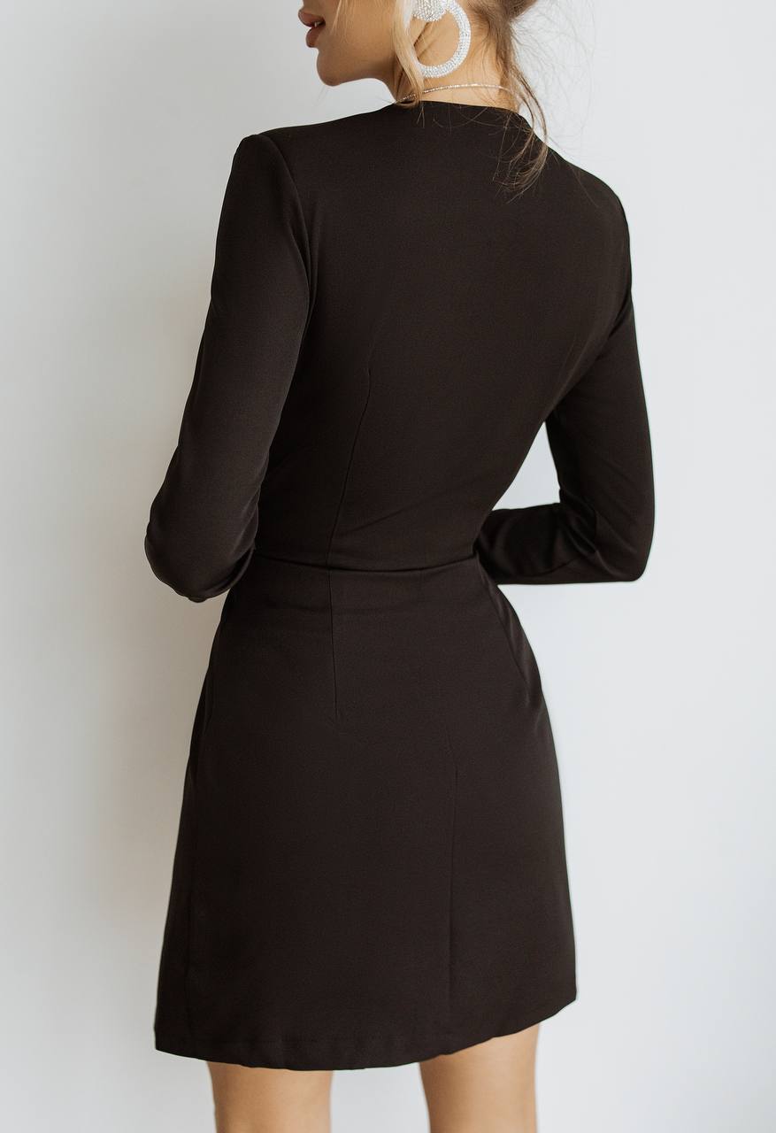 Black long-sleeve dress worn by a person against a white background