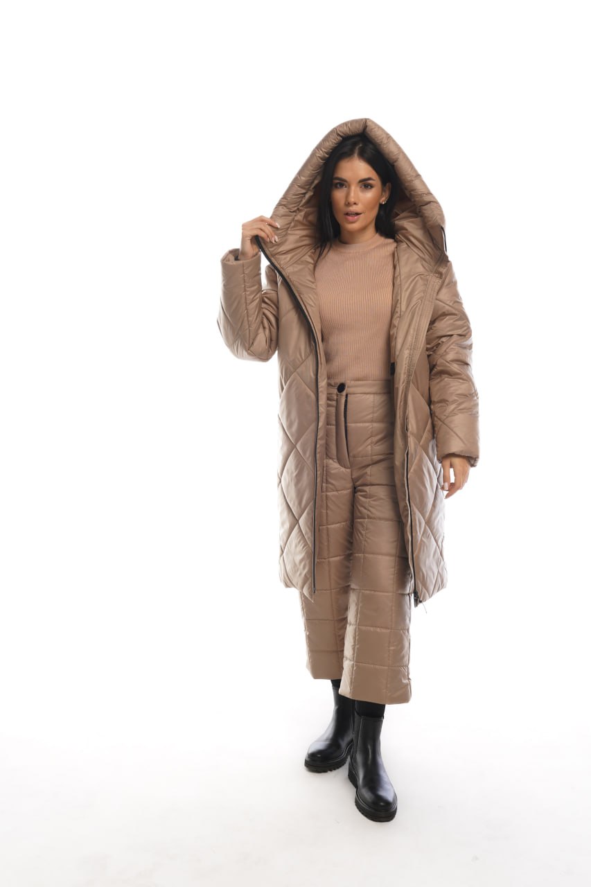 Woman wearing a long beige quilted coat on a white background