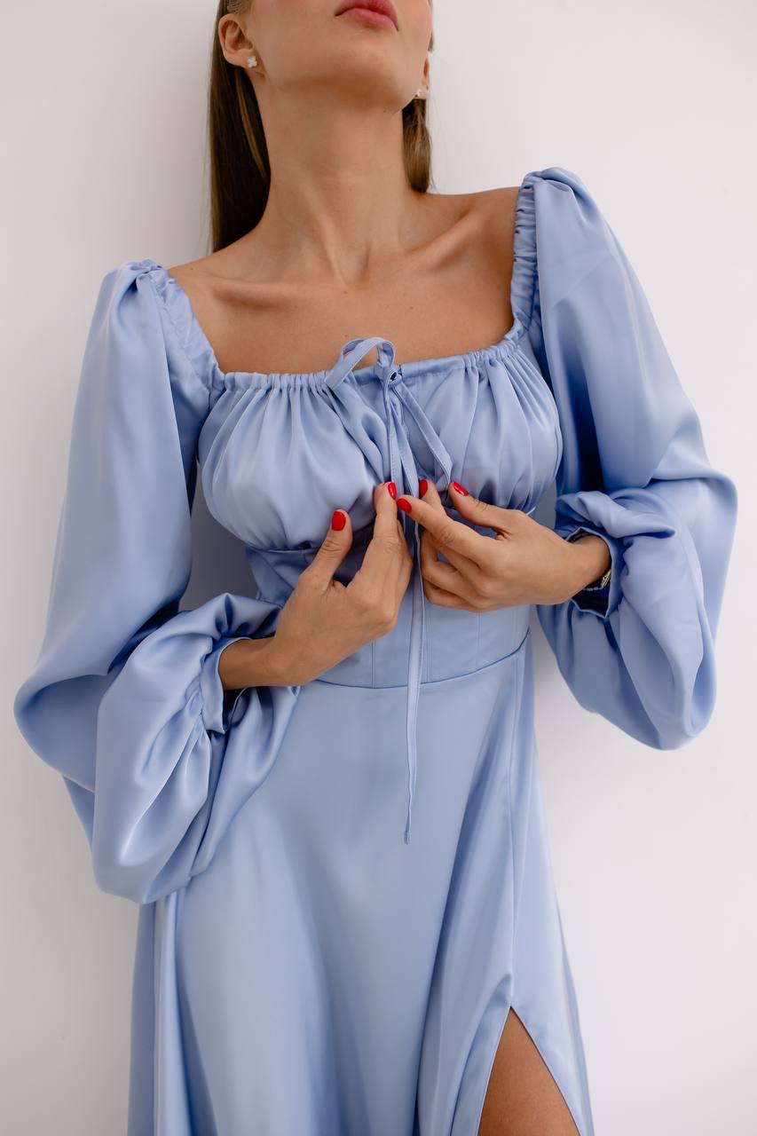 Woman wearing a light blue dress with long sleeves against a white background