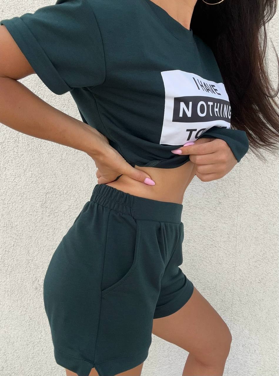 Person wearing a dark green t-shirt and shorts with text on a light background