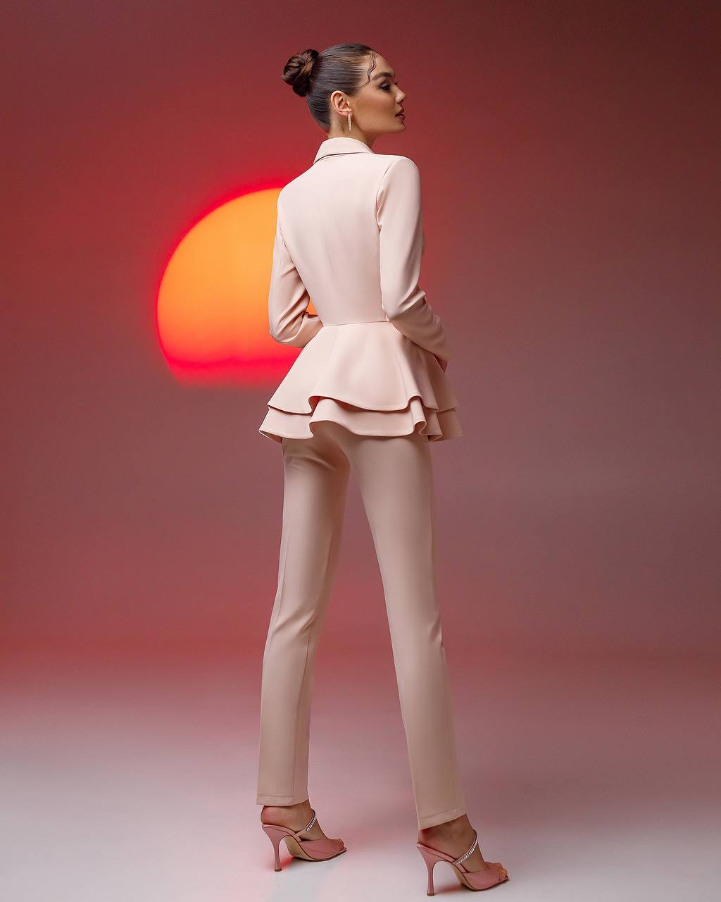 Woman in a beige suit standing with a sunset in the background