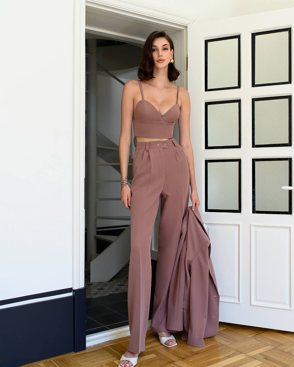Woman in a mauve outfit standing in a doorway.