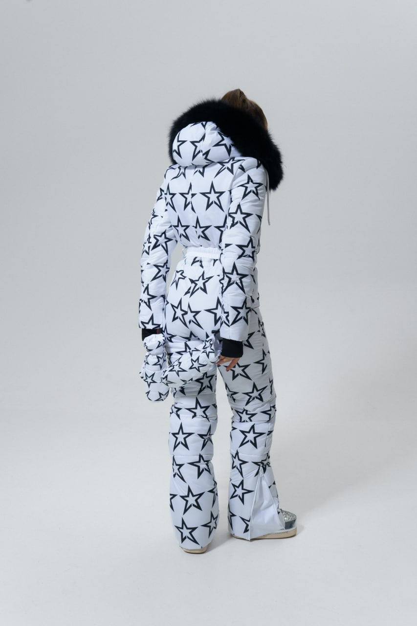 Person wearing a white snowsuit with black star patterns on a plain background