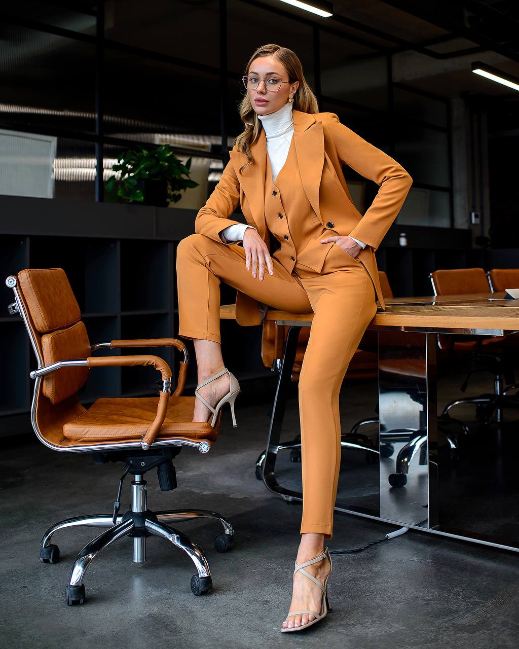 Woman in a mustard yellow suit sitting in an office chair.