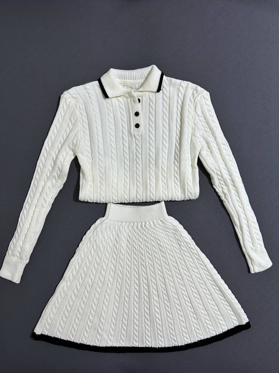 White cable knit sweater and skirt set on a dark gray background