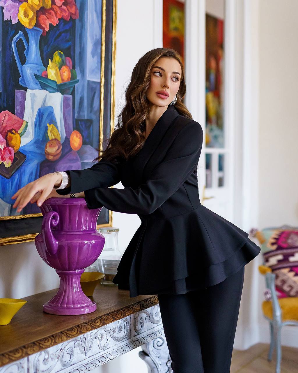 Woman in a black outfit standing in a room with artistic decor