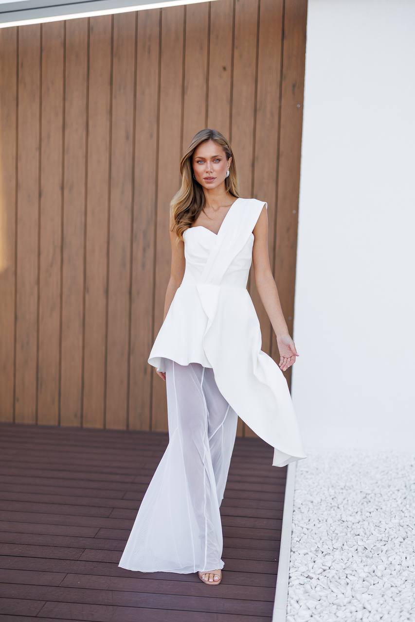 Woman in a white dress standing on a wooden deck with a wooden wall background