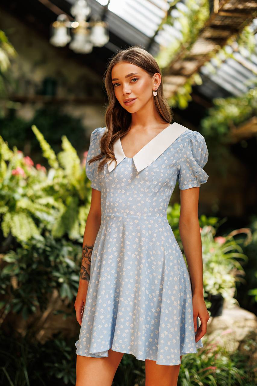 Woman wearing a light blue dress with white collar in a garden setting