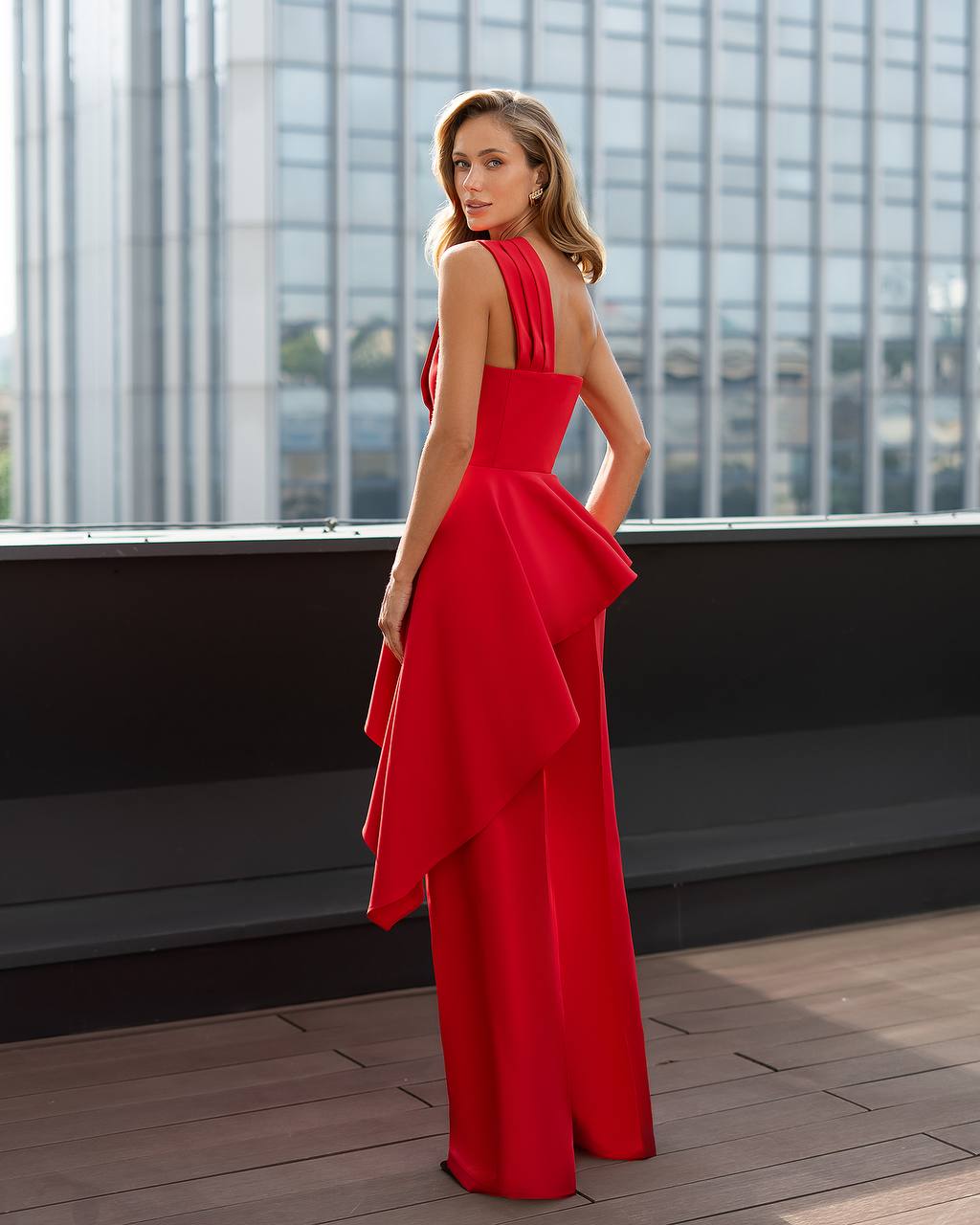 Woman in a red dress standing on a rooftop with cityscape background