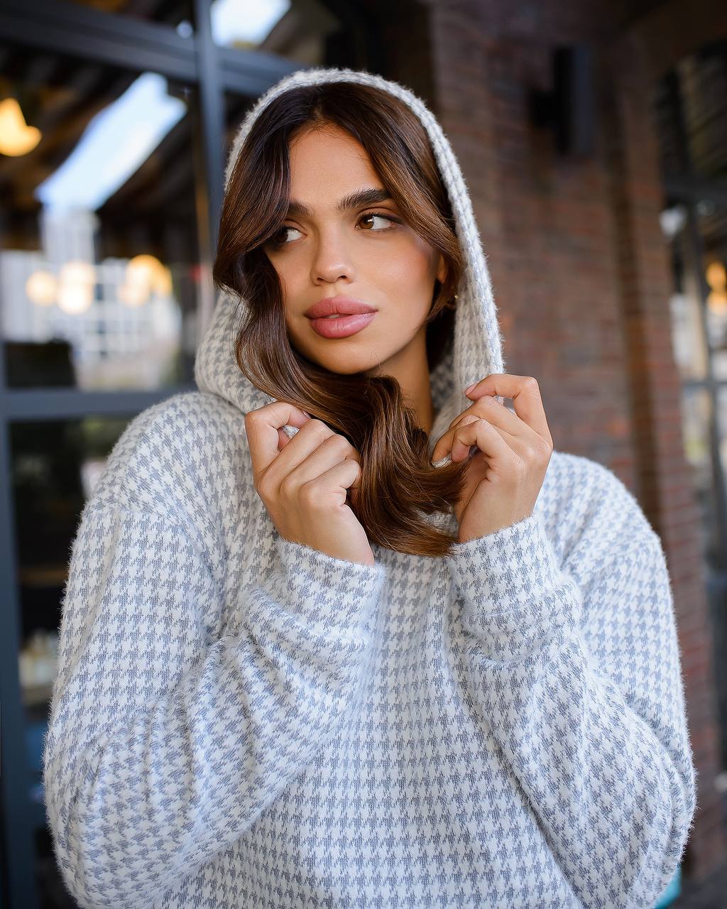 Woman wearing a gray knitted hoodie in an urban setting