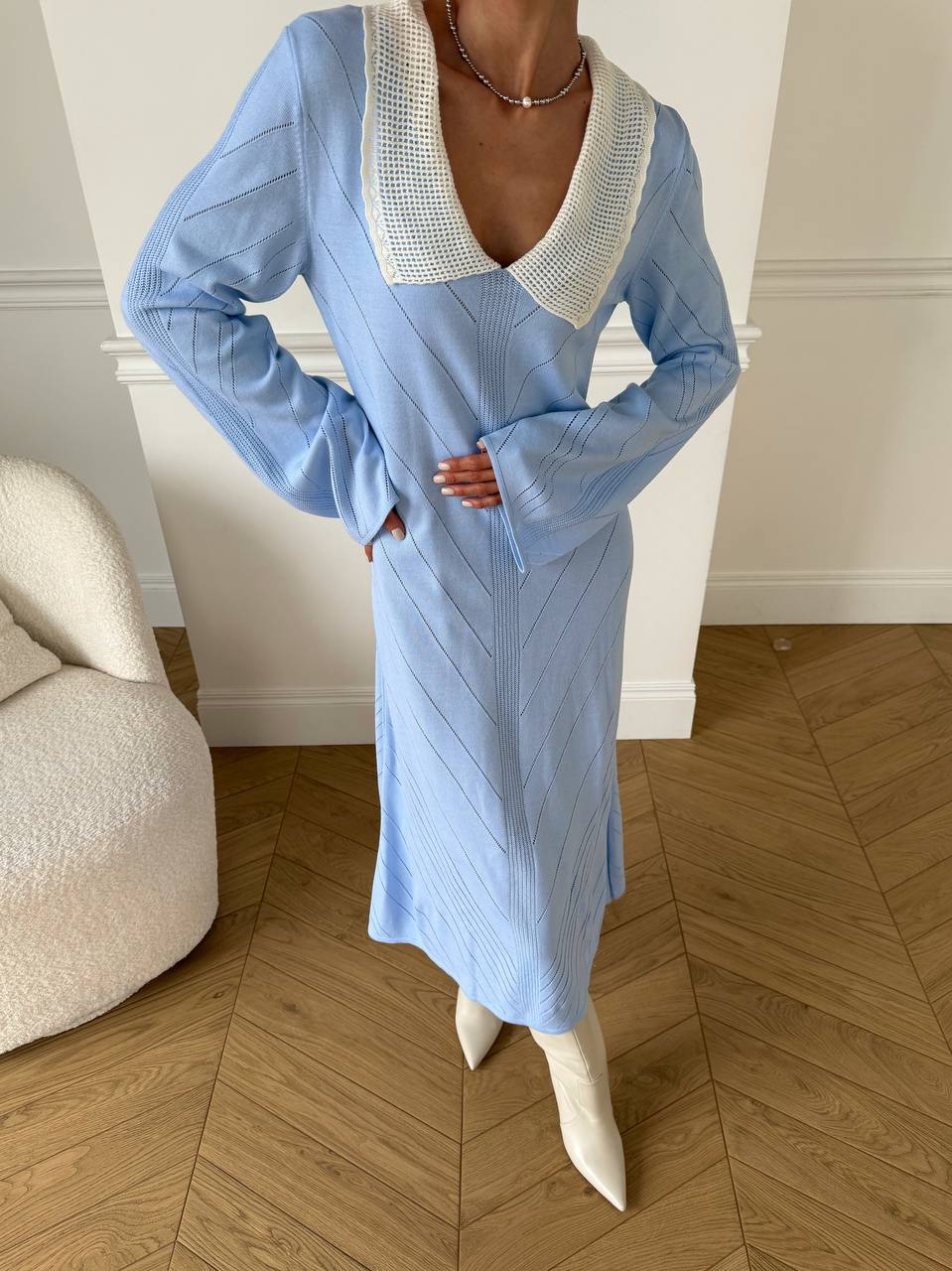 Person wearing a blue dress with a white collar in an indoor setting