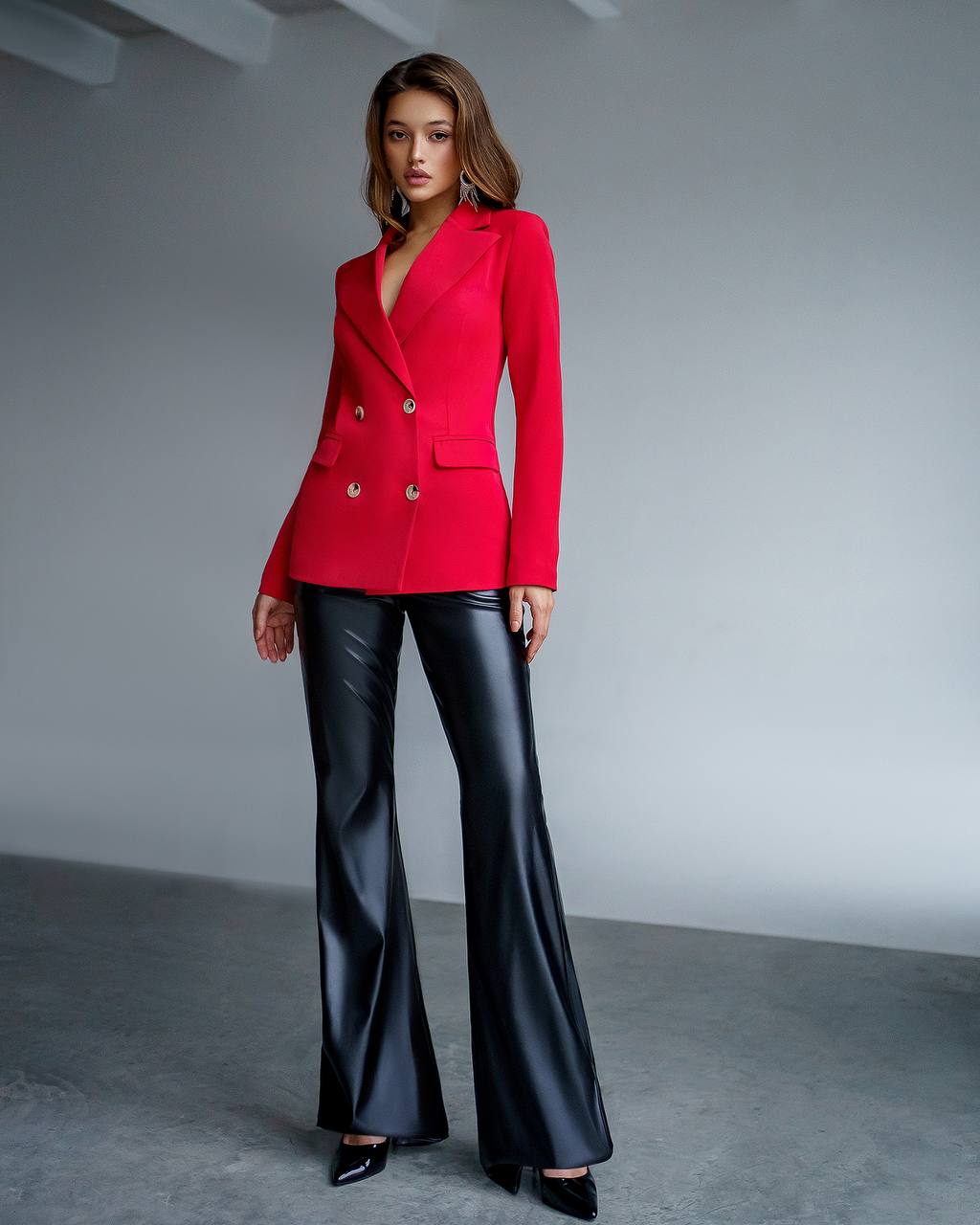Woman wearing a red blazer and black pants against a gray background