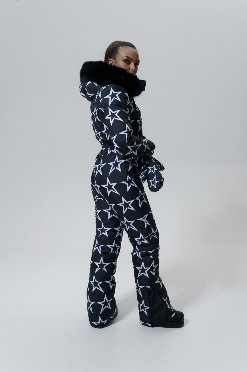 Person wearing a black and white star-patterned snowsuit on a white background