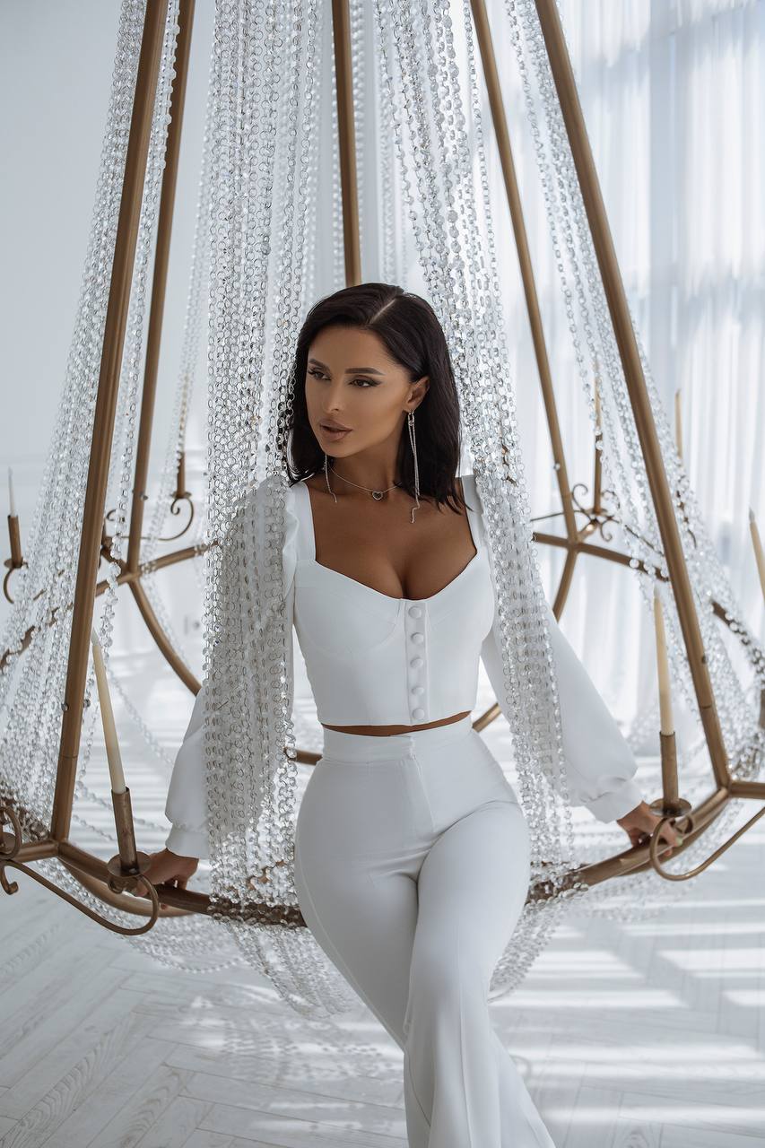 Woman in a white outfit sitting on a decorative swing with a blurred background