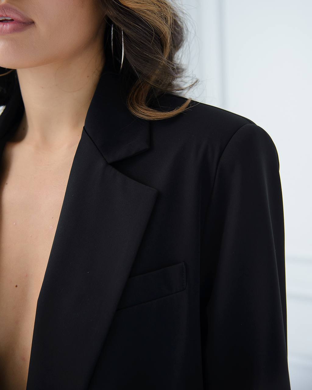 Close-up of a person wearing a black blazer against a white background