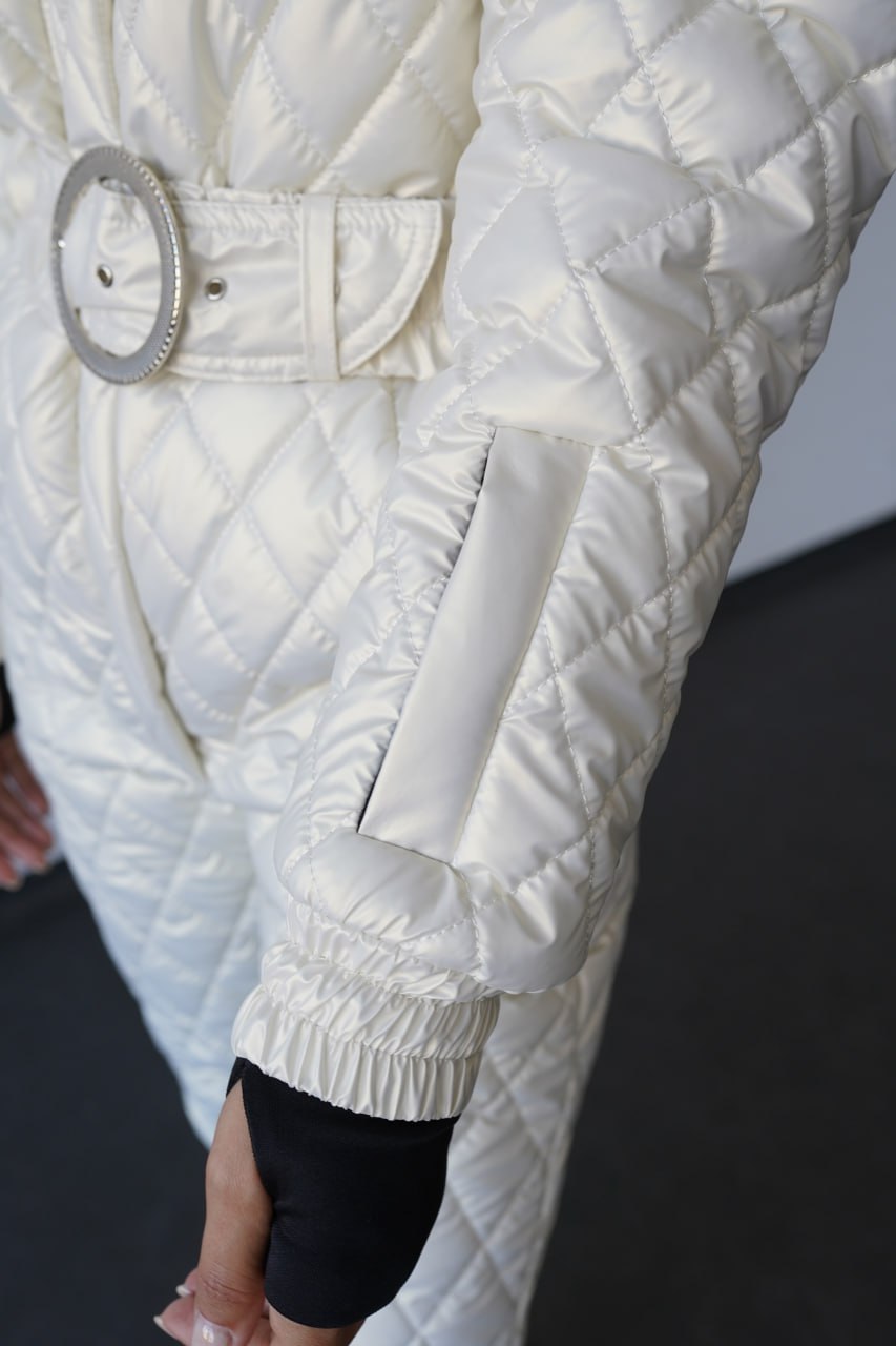 Close-up of a person wearing a white quilted jacket with a belt.