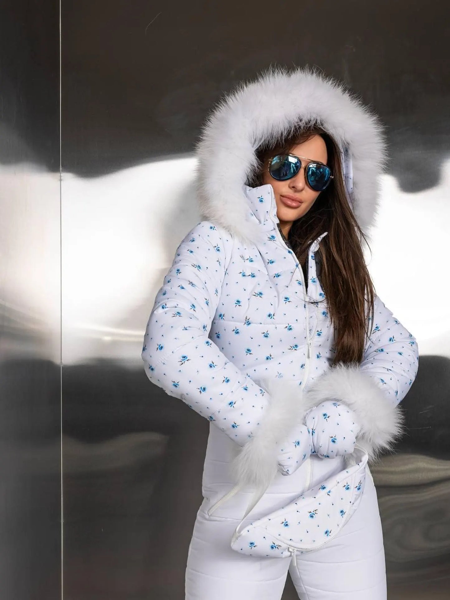 Woman wearing a white winter coat with fur hood and mittens in a snowy setting