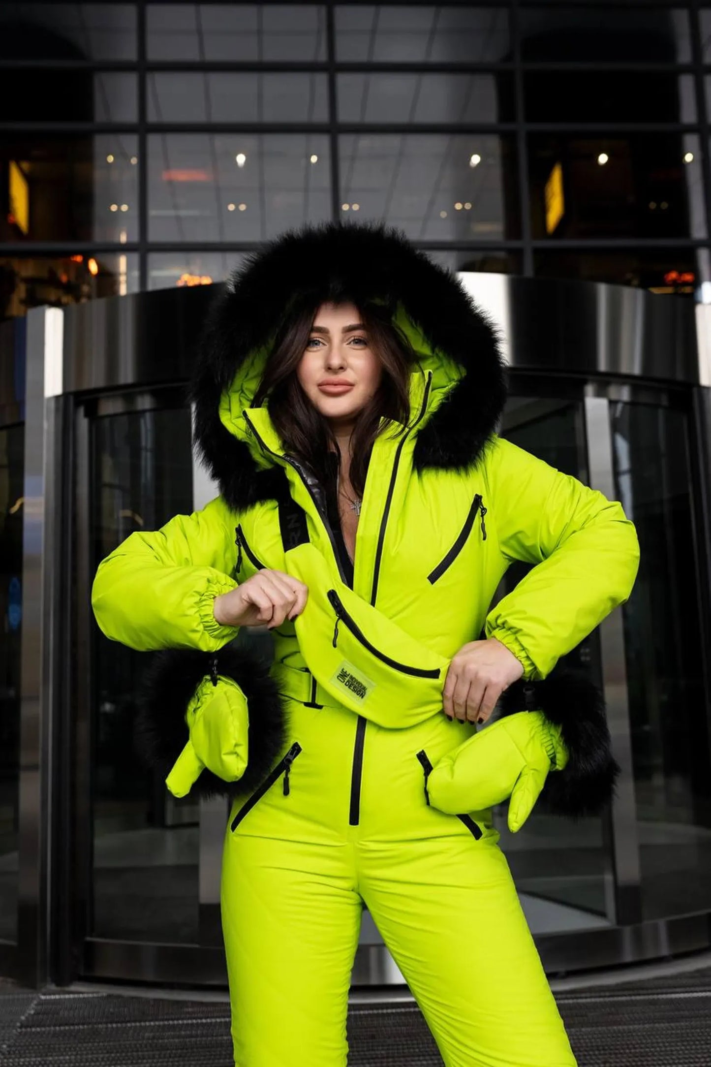 Person wearing a bright yellow-green snowsuit with black fur hood in an indoor setting.
