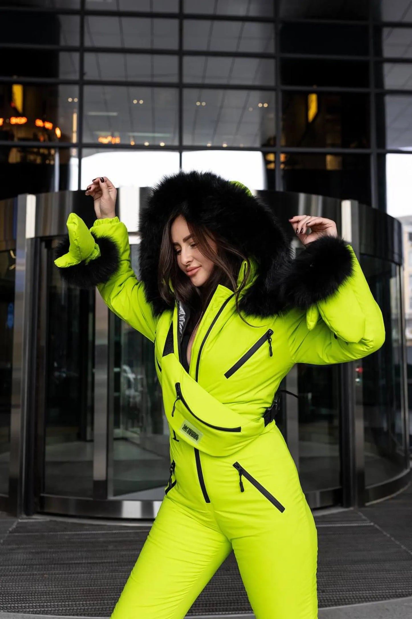 Person wearing a bright yellow snowsuit with black fur trim in an urban setting.