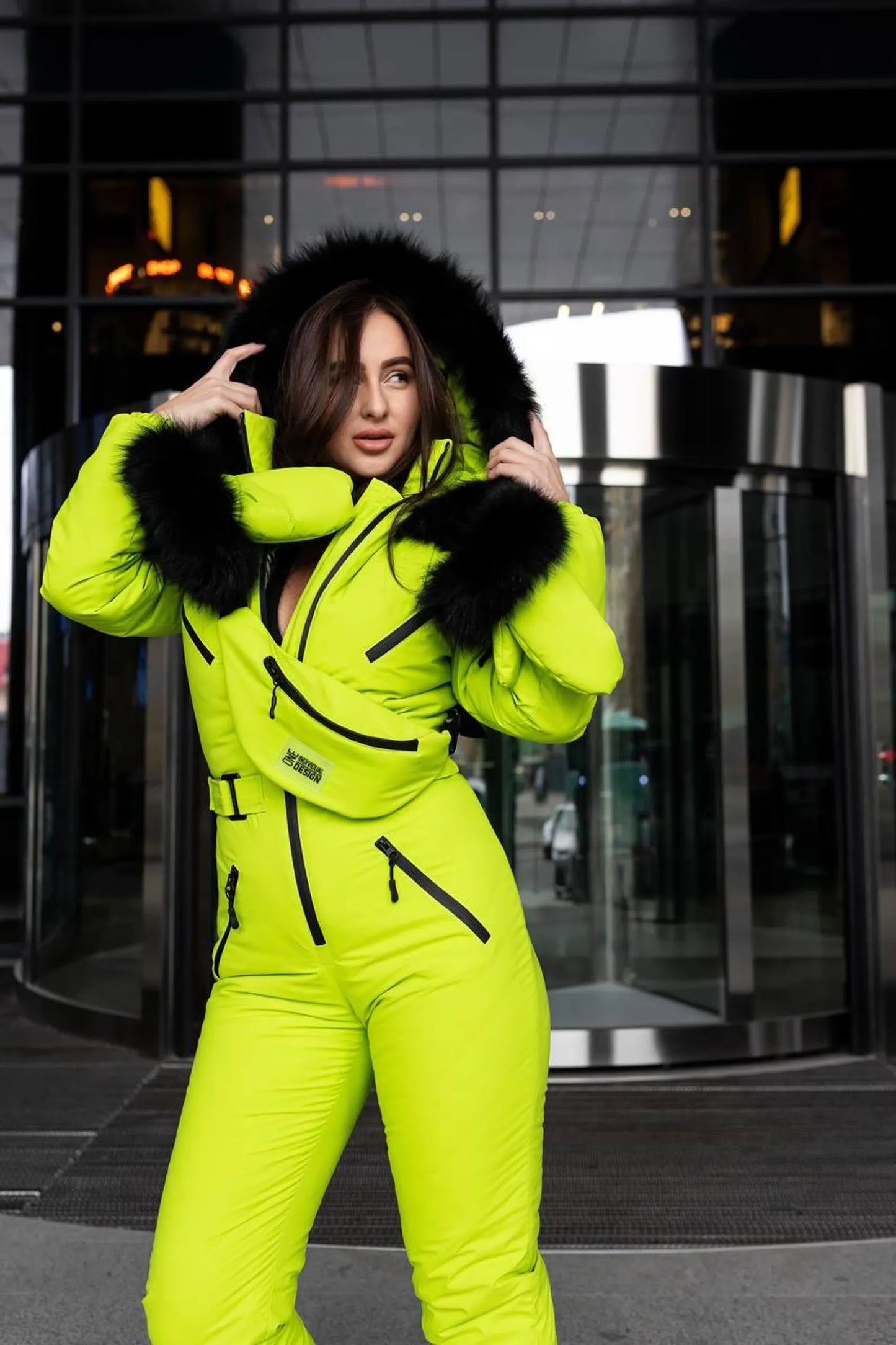 Person wearing a bright yellow snowsuit with black fur trim in an urban setting.