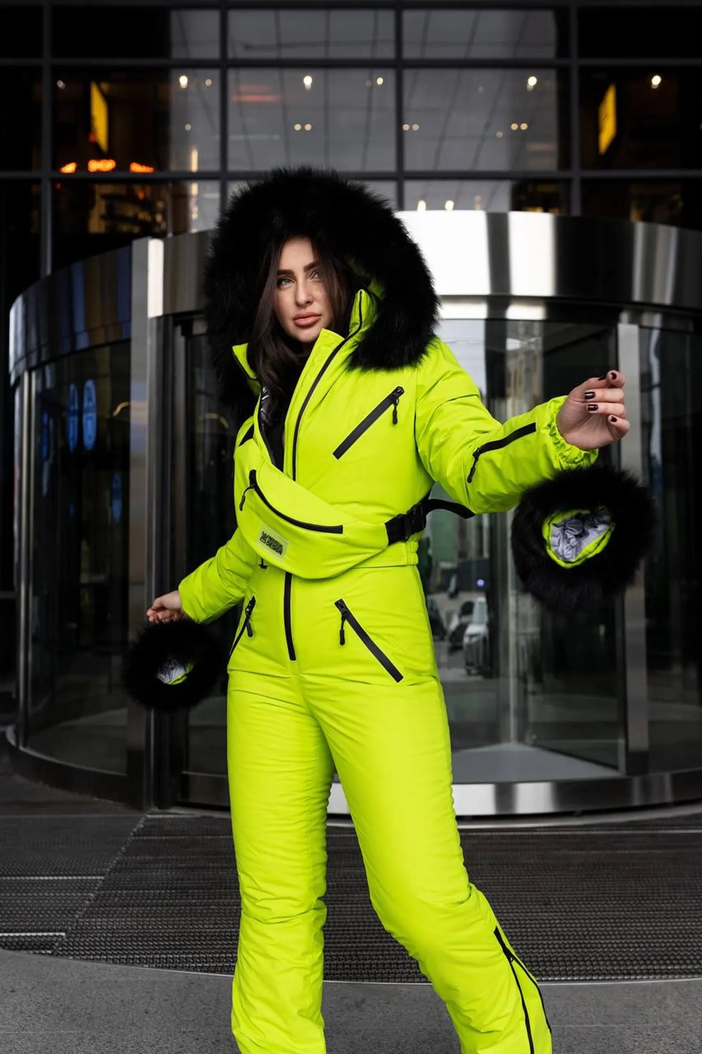 Person wearing a bright yellow snowsuit with black fur trim in an urban setting.