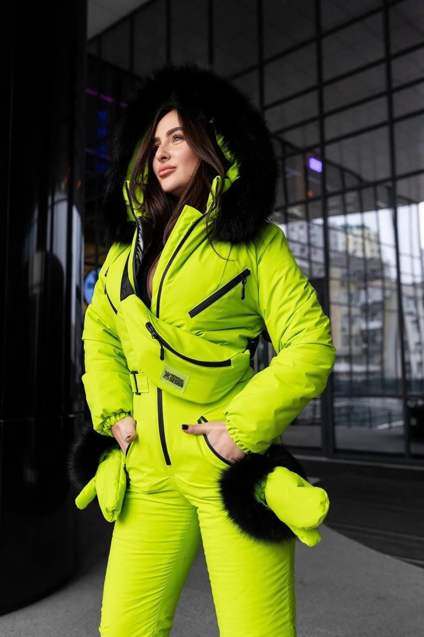 Person wearing a bright green snowsuit with black fur trim in an urban setting