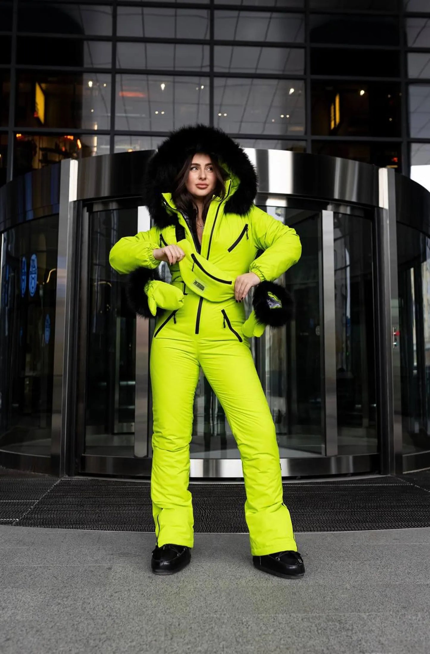 Person wearing a bright yellow snowsuit standing in front of a glass door.