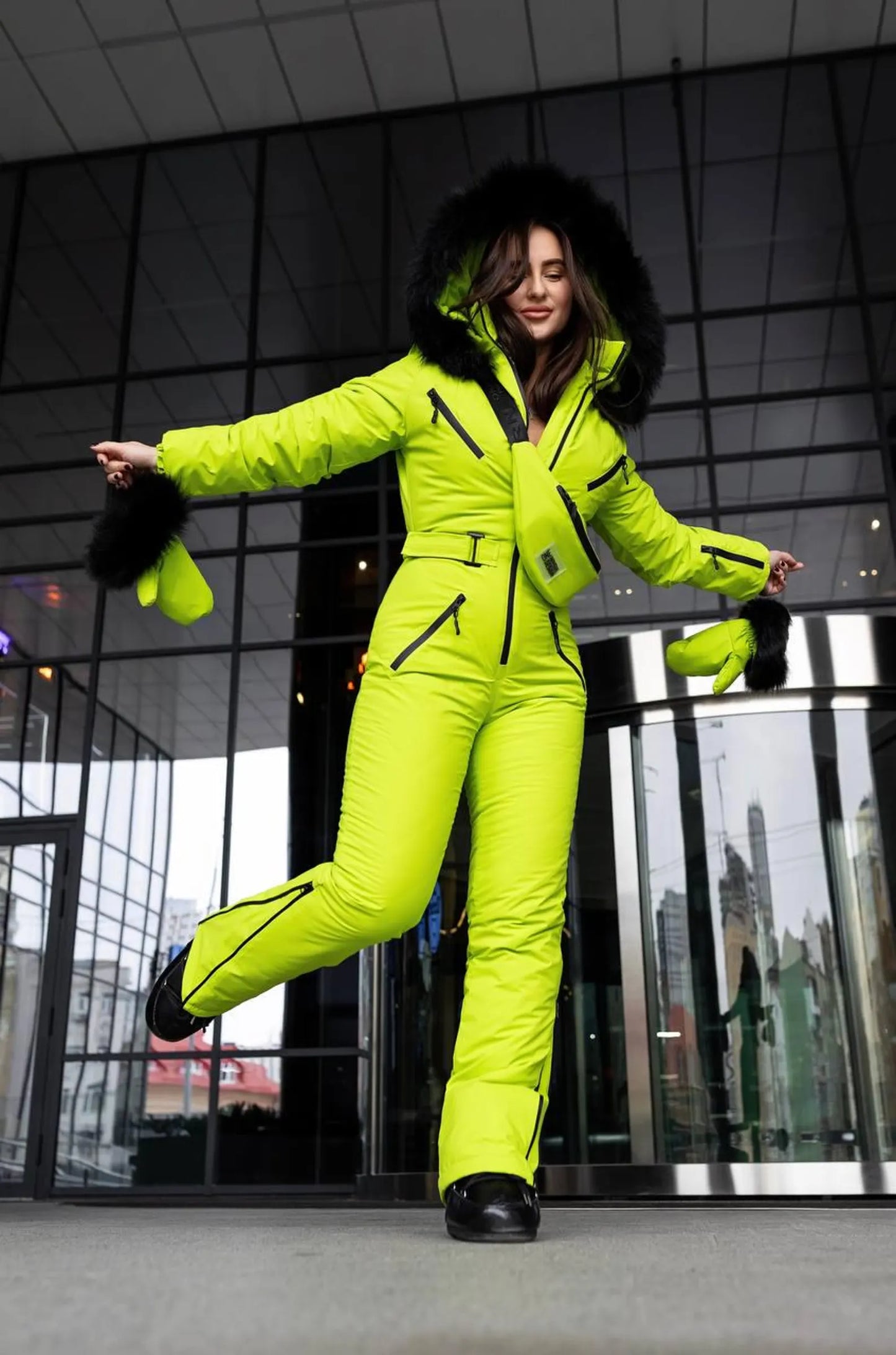 Person wearing a bright yellow snowsuit with black fur trim in an indoor setting.