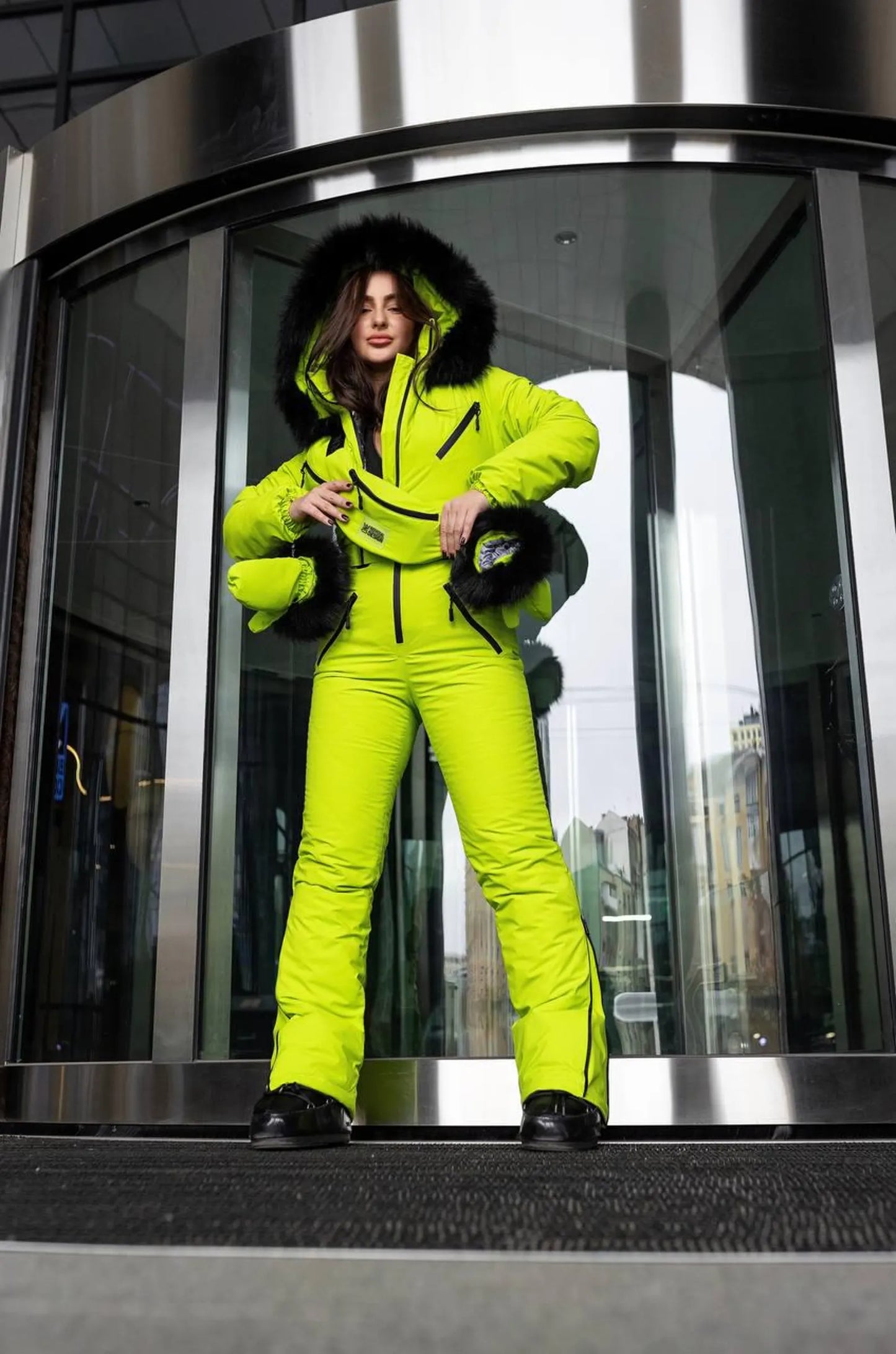 Person wearing a bright yellow snowsuit exiting a revolving door.