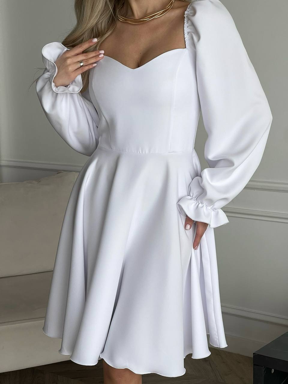 White dress with long sleeves worn by a person, against a neutral background