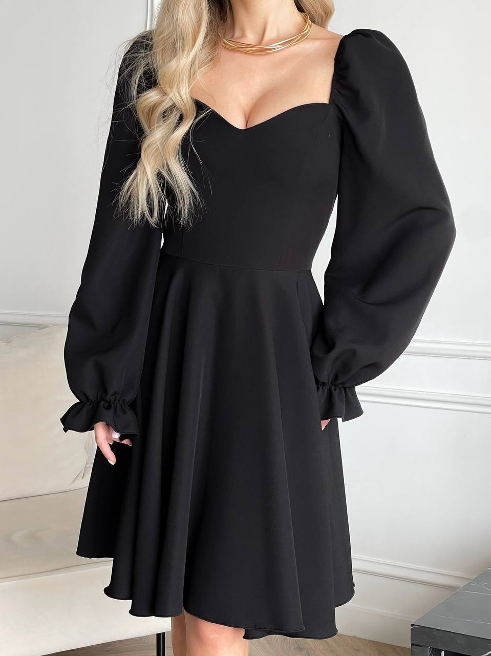 Black dress with puffed sleeves worn by a person against a neutral background