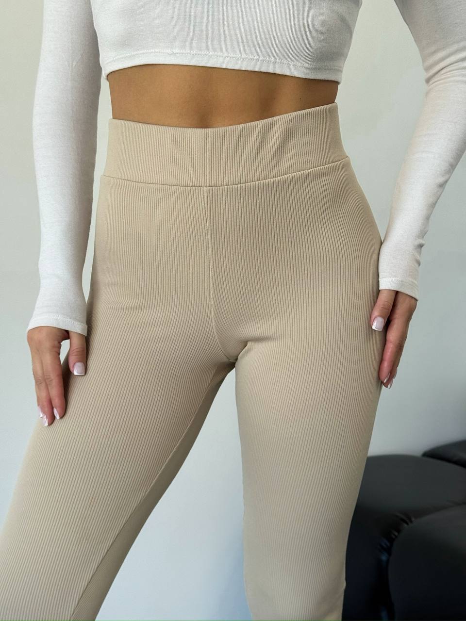 Beige leggings worn with a white long-sleeve top against a neutral background