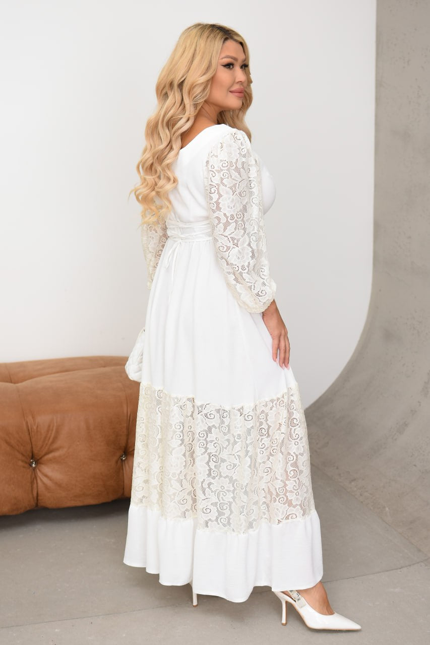 Woman wearing a white lace dress standing against a neutral background