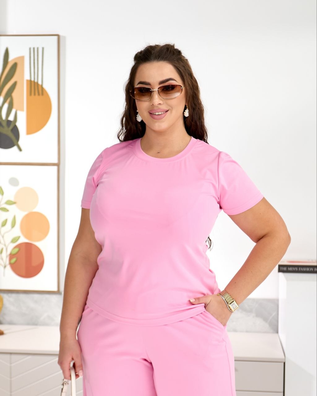 Woman wearing a pink outfit in a room with abstract art on the wall.