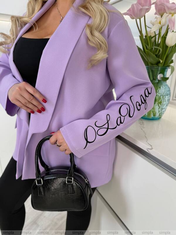 Person wearing a purple coat with 'O La Voga' text, holding a black handbag indoors.