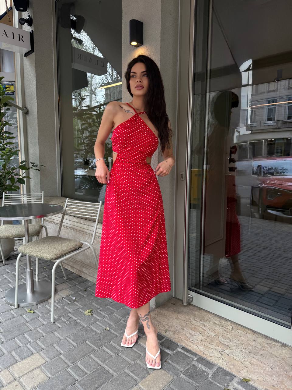 Woman in a red dress standing outside a store with glass doors.