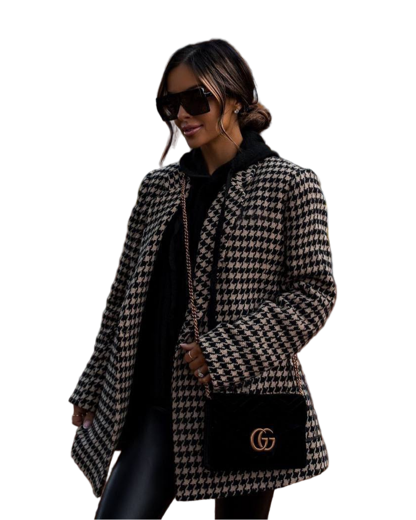 Woman wearing a houndstooth patterned coat with a black handbag featuring a logo on a white background