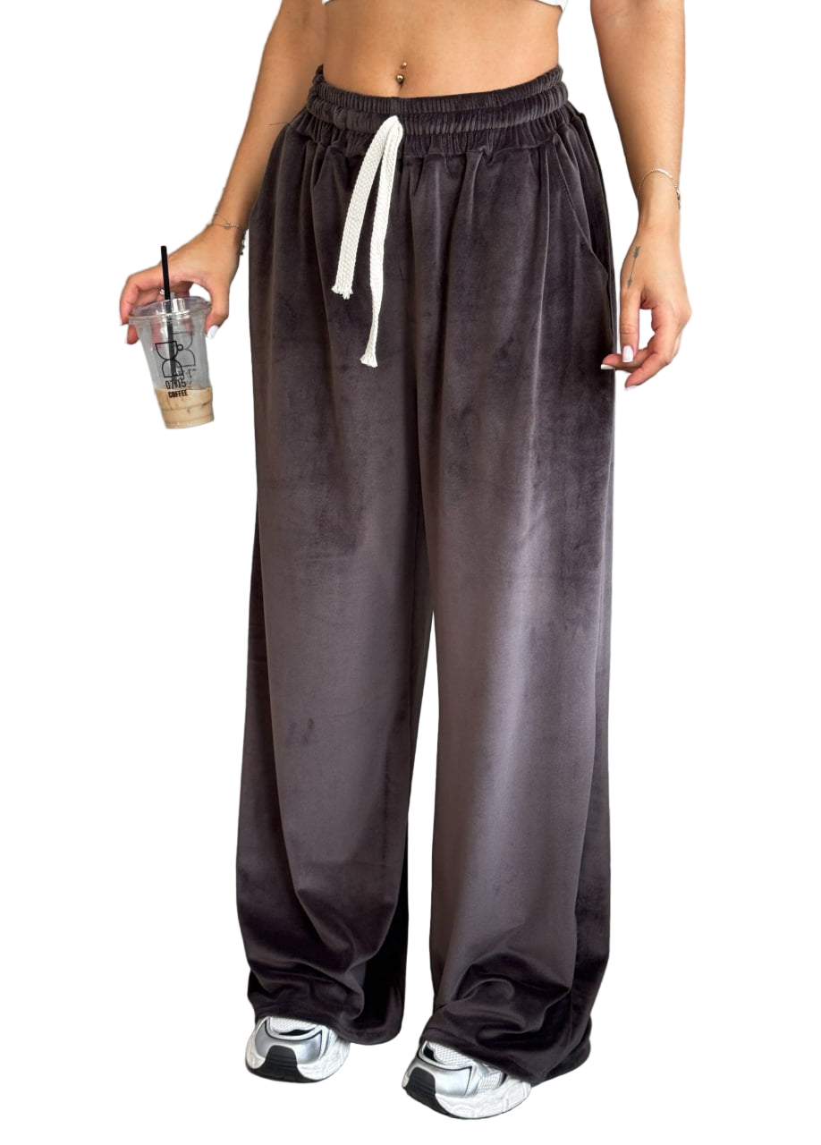 Person wearing dark gray sweatpants with a white drawstring, holding a drink.