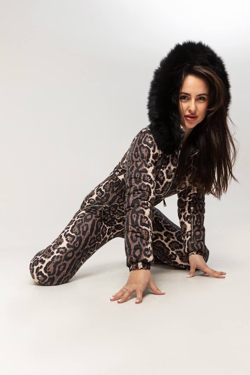 Person wearing a leopard print onesie with a fur-lined hood on a white background