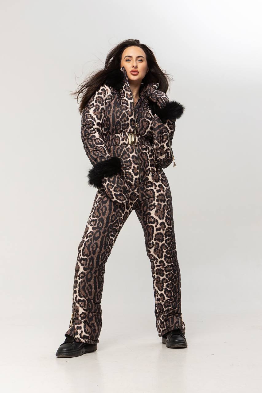 Person wearing a leopard print snowsuit with black fur trim on a white background