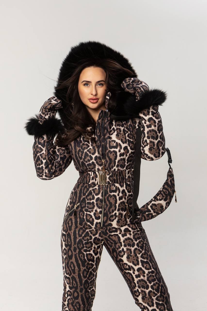 Person wearing a leopard print snowsuit with black fur trim on a white background