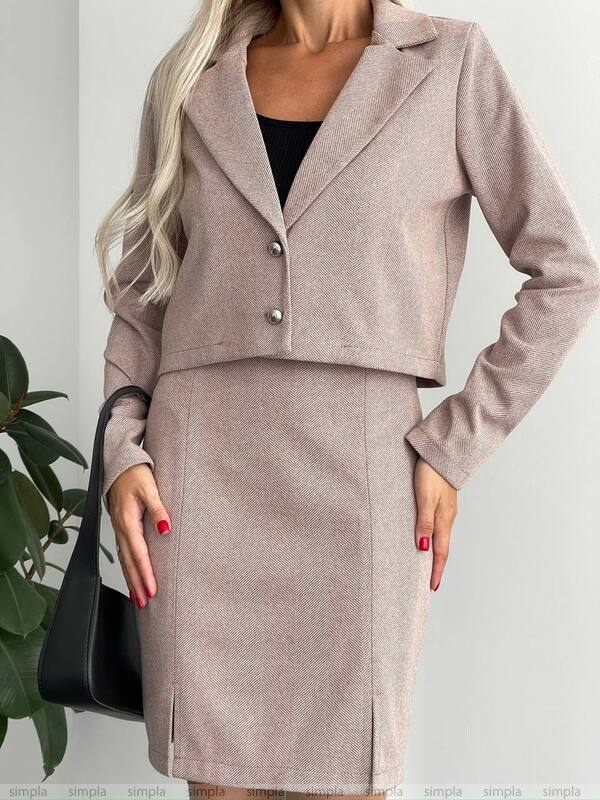 Woman wearing a beige suit with a black handbag on a light gray background