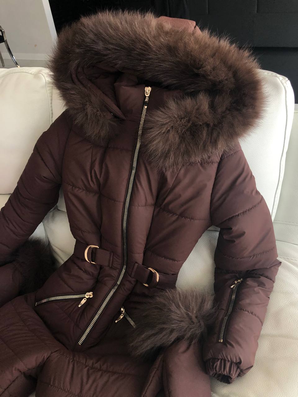 Brown puffer coat with fur hood on a white couch