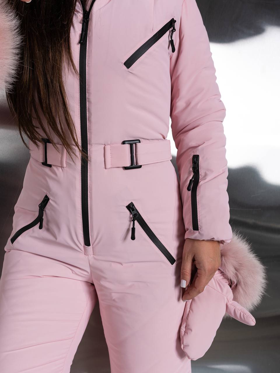 Person wearing a pink snowsuit with black zippers and fur accents.