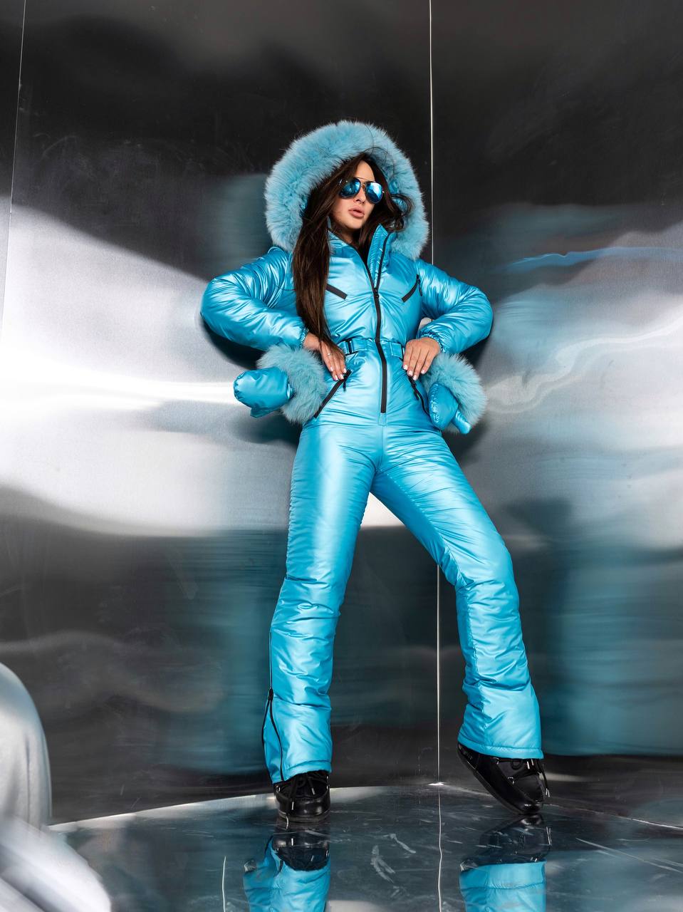 Person wearing a blue snowsuit with a hood in a reflective surface setting